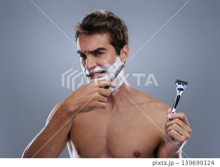 Man, choice and razor in studio, shaving cream or portrait for grooming by grey background. Person, model and decision for blade with beard, facial hair removal and doubt product for cosmetic change 139699124