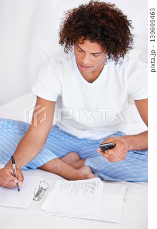 Working, man in bedroom and cellphone for work from home, writing and sitting in pyjamas for freelance. Technology, entrepreneur and remote worker for online job, documents and business projects Working, man in bedroom and cellphone for work from home, writing and sitting in pyjamas for freelance. Technology, entrepreneur and remote worker for online job, documents and business projects 139699463