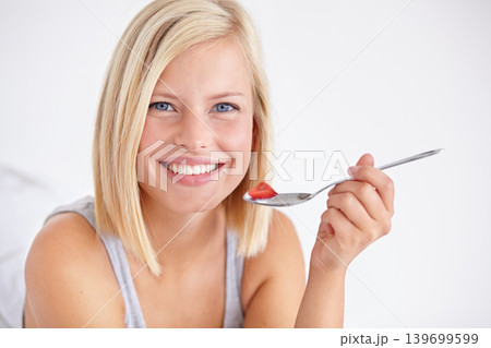 Portrait, happy woman and eating fruit salad, healthy diet or nutrition in home bedroom. Face smile, spoon or person with strawberry, hungry for breakfast or organic food for wellness in the morning Portrait, happy woman and eating fruit salad, healthy diet or nutrition in home bedroom. Face smile, spoon or person with strawberry, hungry for breakfast or organic food for wellness in the morning 139699599
