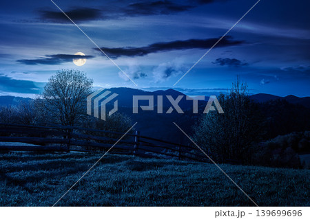 mountainous rural landscape in spring at night. mysterious view of valley fields. full moon over alpine meadow. carpathian mountains countryside with forest near pasture. agricultural fantasy mountainous rural landscape in spring at night. mysterious view of valley fields. full moon over alpine meadow. carpathian mountains countryside with forest near pasture. agricultural fantasy 139699696