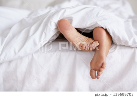 Bed, feet and person sleeping in home, relax and resting nap in sheets for health, calm and leisure in the morning. Foot, bedroom and closeup of toes in blanket, skin of legs and comfort in house Bed, feet and person sleeping in home, relax and resting nap in sheets for health, calm and leisure in the morning. Foot, bedroom and closeup of toes in blanket, skin of legs and comfort in house 139699705