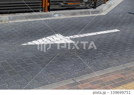 Road marking pointing forward on a gray pavement in a city near a parking area with nearby structures and barriers Road marking pointing forward on a gray pavement in a city near a parking area with nearby structures and barriers 139699751