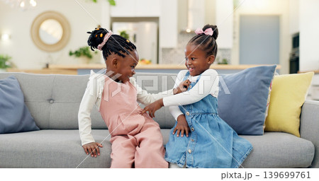 Kids, play and couch in a home with poke, smile and happy from sibling bonding together. House, lounge sofa and daughter friends with game and girl friendship with fun and youth in a living room 139699761