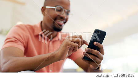 Hands, typing and a black man with a phone on the sofa for social media, connection or communication. Smile, relax and an African person with a mobile for an app, email or notification in a house Hands, typing and a black man with a phone on the sofa for social media, connection or communication. Smile, relax and an African person with a mobile for an app, email or notification in a house 139699819