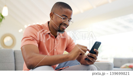 Happy, typing and a black man with a phone on the sofa for social media, connection or communication. Smile, relax and an African person with a mobile for an app, email or notification in a house 139699821