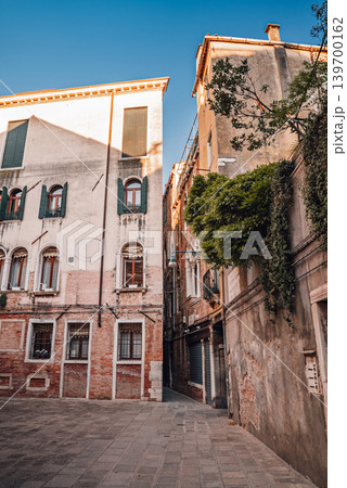Atmospheric empty Venetian street with historic Italian architecture at daylight Atmospheric empty Venetian street with historic Italian architecture at daylight 139700162