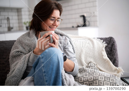 Happy Woman Relaxing At Home With A Cup Of Hot Drink On A Couch 139700290