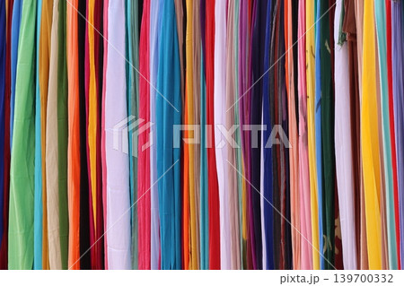 Vibrant textiles hang neatly in a colorful row 139700332