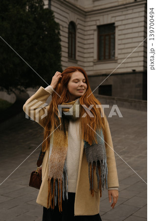red-haired girl with long red hair enjoys the cool weather in a city street during fall season red-haired girl with long red hair enjoys the cool weather in a city street during fall season 139700494
