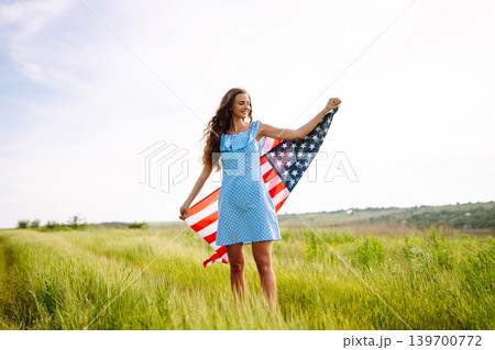 Young woman with american USA flag on blooming meadow. Independence Day, 4th July. Young woman with american USA flag on blooming meadow. Independence Day, 4th July. 139700772