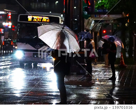 雨夜の停留所、バスのヘッドライトが映し出す男性のシルエット 雨夜の停留所、バスのヘッドライトが映し出す男性のシルエット 139701016