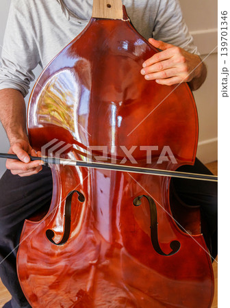 Bass player trying to play broken stringless contrabass. Paradox, persistence, and an impossible effort in hope to make a damaged instrument sound. Bass player trying to play broken stringless contrabass. Paradox, persistence, and an impossible effort in hope to make a damaged instrument sound. 139701346