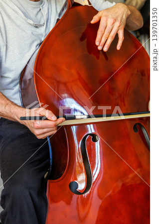 Bass player trying to play broken stringless contrabass. Paradox, persistence, and an impossible effort in hope to make a damaged instrument sound. 139701350