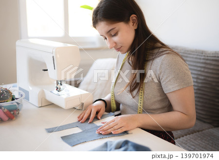 Young girl sewing a piece of fabric at home in the daytime With The sewing machine 139701974