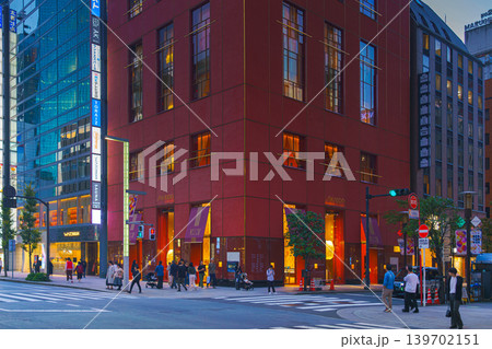 Tokyo, Japan - Oct 14 2024, panoramic view of main street of Ginza district, tall glass facades of skyscrapers along which people walk, cars drive along road, in evening with illumination, Tokyo Japan 139702151