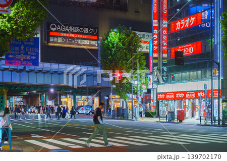 Tokyo, Japan - Oct 14 2024, panoramic view of people crossing road at pedestrian crossing in Ginza district, with many illuminated signage on facades of skyscrapers in background and cars Tokyo, Japan - Oct 14 2024, panoramic view of people crossing road at pedestrian crossing in Ginza district, with many illuminated signage on facades of skyscrapers in background and cars 139702170