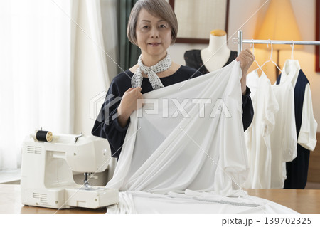 シニア女性のデザイナーがアトリエで洋服を作る シニア女性のデザイナーがアトリエで洋服を作る 139702325