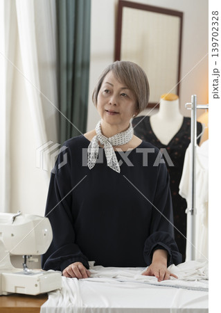 シニア女性のデザイナーがアトリエで洋服を作る シニア女性のデザイナーがアトリエで洋服を作る 139702328