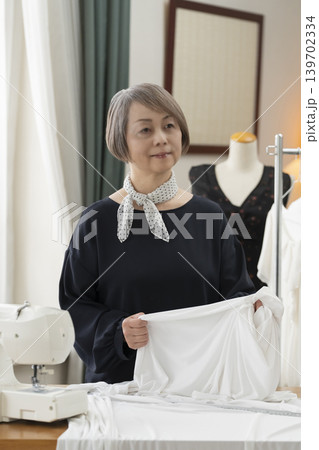 シニア女性のデザイナーがアトリエで洋服を作る シニア女性のデザイナーがアトリエで洋服を作る 139702334