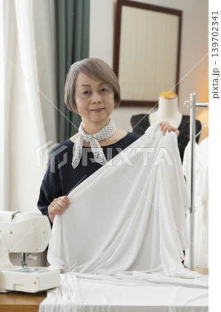 シニア女性のデザイナーがアトリエで洋服を作る シニア女性のデザイナーがアトリエで洋服を作る 139702341