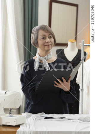 シニア女性のデザイナーがアトリエで洋服を作る シニア女性のデザイナーがアトリエで洋服を作る 139702346