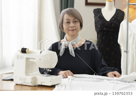 シニア女性のデザイナーがアトリエで洋服を作る シニア女性のデザイナーがアトリエで洋服を作る 139702353