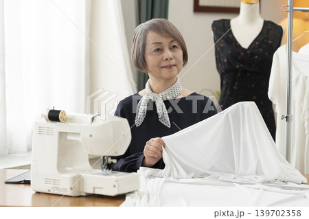 シニア女性のデザイナーがアトリエで洋服を作る シニア女性のデザイナーがアトリエで洋服を作る 139702358