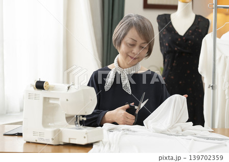 シニア女性のデザイナーがアトリエで洋服を作る シニア女性のデザイナーがアトリエで洋服を作る 139702359