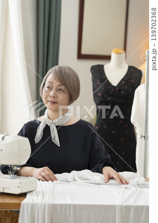 シニア女性のデザイナーがアトリエで洋服を作る シニア女性のデザイナーがアトリエで洋服を作る 139702368