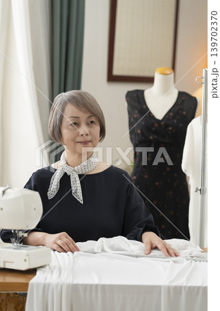 シニア女性のデザイナーがアトリエで洋服を作る シニア女性のデザイナーがアトリエで洋服を作る 139702370