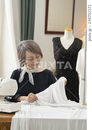 シニア女性のデザイナーがアトリエで洋服を作る 139702371