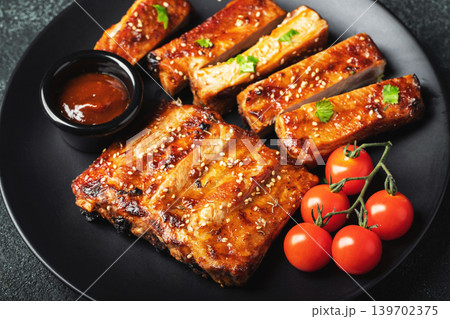 Hot grilled spare ribs from a summer BBQ served on a plate with sauce. Top view. Copy space Hot grilled spare ribs from a summer BBQ served on a plate with sauce. Top view. Copy space 139702375