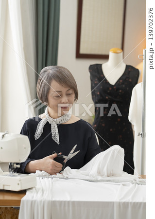 シニア女性のデザイナーがアトリエで洋服を作る 139702376