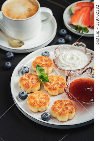Cottage cheese pancakes, syrniki, curd fritters decorated with strawberry and raspberry served on a white plate. Homemade breakfast concept 139702382