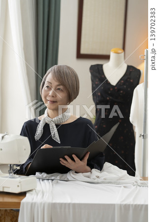 シニア女性のデザイナーがアトリエで洋服を作る シニア女性のデザイナーがアトリエで洋服を作る 139702383