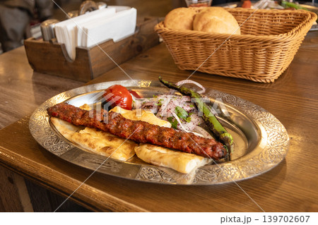 Traditional Turkish dish, Adana Kebab is long kebab of minced meat served with fried hot peppers, tomatoes, fresh onions and herbs. Traditional Turkish dish, Adana Kebab is long kebab of minced meat served with fried hot peppers, tomatoes, fresh onions and herbs. 139702607