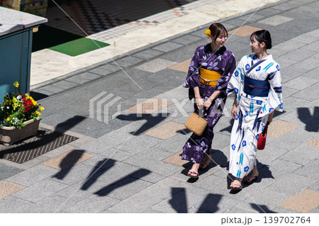 浴衣姿で古い街並みを笑顔で散策する2人の若い女性 俯瞰 浴衣姿で古い街並みを笑顔で散策する2人の若い女性 俯瞰 139702764