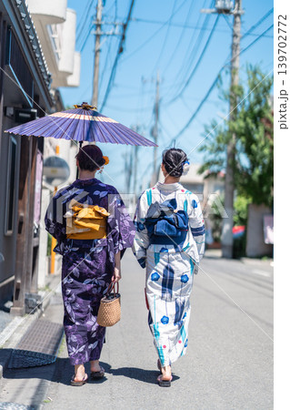 日傘を差して和の街並みを歩く浴衣姿の女性2人の後ろ姿 日傘を差して和の街並みを歩く浴衣姿の女性2人の後ろ姿 139702772