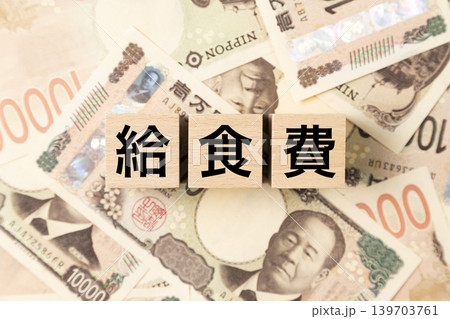 「給食費」と書かれたブロックとたくさんの一万円札 「給食費」と書かれたブロックとたくさんの一万円札 139703761