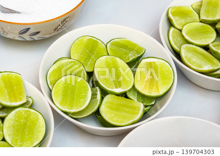 The close up view of the many chopped lime pieces put in the white ceramic bowls as an ingredient or condiment of food, placed on table. The close up view of the many chopped lime pieces put in the white ceramic bowls as an ingredient or condiment of food, placed on table. 139704303