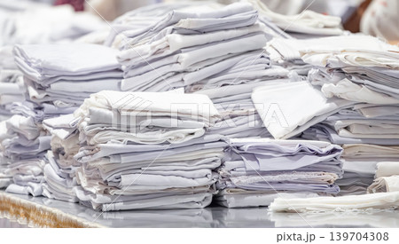 Stacks of folded white fabric on a smooth table organized piles clean textile storage preparation material handling. Stacks of folded white fabric on a smooth table organized piles clean textile storage preparation material handling. 139704308