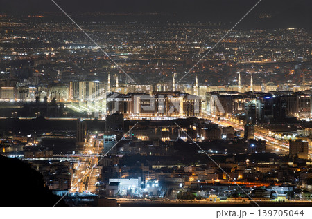 Elevated nighttime panorama of the city of Madinah from Mount Uhud featuring the Prophet's Mosque and urban street lights in Saudi Arabia. 139705044