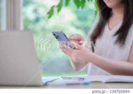 スマートフォンを見ながら勉強する若い女性 139705694