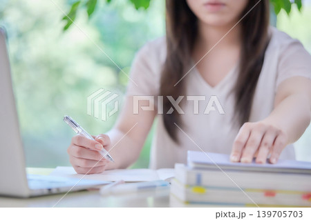 パソコンを見ながら勉強する若い女性 パソコンを見ながら勉強する若い女性 139705703