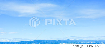 夏の青空の北海道美瑛町周辺の上空を飛ぶ旭川空港に向かう飛行機 139706599