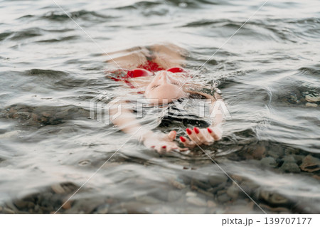 Woman, water, relaxation, peaceful woman floating on her back in calm water during summer vacation. Woman, water, relaxation, peaceful woman floating on her back in calm water during summer vacation. 139707177