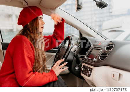 Woman driving car focused female wearing red beret and sweater steering vehicle through city street during daily commute 139707178