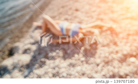 Beach woman bikini relaxing on sunlit pebble shore during summer vacation with artistic blur and copy space 139707180