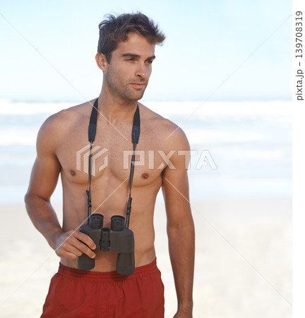 Man, binoculars and lifeguard on beach for security, emergency or health and safety. Face of young male person in fitness for monitoring, bay watch or patrol by the ocean coast or sea in surveillance 139708319