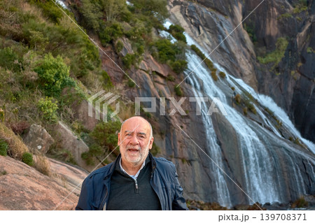 Mature man posing in front of the majestic Ezaro waterfall in A Coruna, Spain 139708371
